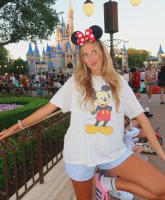 a woman posing for a photo in front of the disney mouse castle at disneyland world