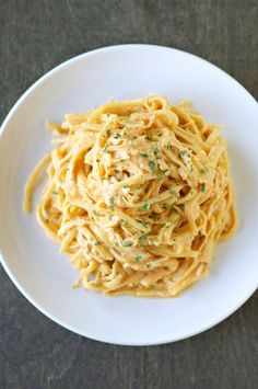 a white plate topped with pasta covered in sauce and parmesan sprinkles