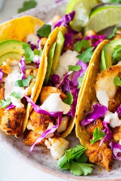 two fish tacos on a plate with coleslaw and avocado