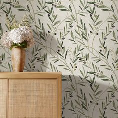 a vase filled with flowers sitting on top of a wooden dresser next to a wall