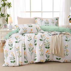 the comforter is made up with flowers and green leaves on it, along with two pillows