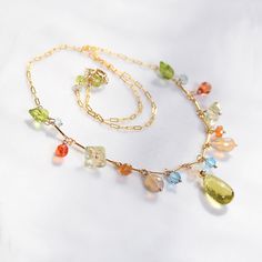 This necklace is so fun! It is dainty and it is adorned dangles of gems in different shapes and sizes.  It features micro faceted and shimmery focal of lemon citrine of Swiss blue topaz rounds, drops and roundels of rainbow fire Ethiopian opal,  twisted roundels of lemon topaz and small briolettes of orange Padparadscha sapphire. Rose bud cut,  bright green peridot briolettes connect two types of chain this choker is made with. 17 inches long this necklace closes with gold filled, spring ring clasp and has  more peridot at the closure.  Lemon citrine in the center 9x14mm Thank you for looking! Please contact me if you have any questions or requests. To see store policies please see here: https://www.etsy.com/shop/agusha?ref=seller-platform-mcnav#policies Ships in a gift box via Priority Ma Rainbow Fire, Padparadscha Sapphire, Gold Filled Necklace, Rose Bud, Green Peridot, Swiss Blue Topaz, Sapphire Blue, Bright Green, Ethiopian Opal