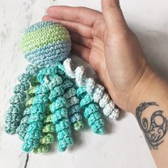 a hand holding a small crocheted object in it's left hand and another item on the right