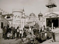 an old black and white photo of people on a street with buildings in the background