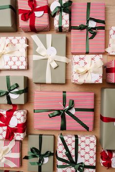 many wrapped presents with bows and ribbons on the table next to each other, all stacked up together