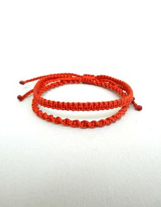 two red string bracelets sitting on top of each other