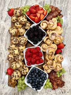 a platter filled with fruit and pastries on top of a wooden cutting board