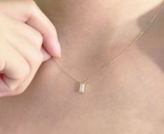 a close up of a person wearing a necklace with a bar on it's back