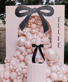 a white cake sitting on top of a table next to balloons and a sign with a bow