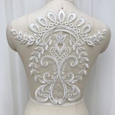 the back of a woman's dress with white embroidery on it