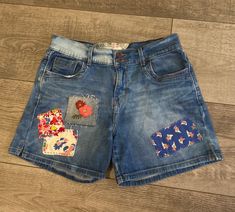 Up-cycled Levi's denim shorts Size 6  hand embroidered denim patch.   waist flat measurements 15" inseam 4 1/2" Summer Denim Bottoms With Floral Patchwork, Medium Wash Cotton Jean Shorts With Floral Embroidery, Summer Recycled Denim Patchwork Bottoms, Summer Patchwork Recycled Denim Bottoms, Upcycled Denim Bottoms For Summer, Cotton Jean Shorts With Floral Embroidery In Medium Wash, Summer Recycled Denim Shorts With Pockets, Spring Denim Bottoms With Patches, Summer Upcycled Denim Bottoms