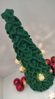 a green knitted christmas tree surrounded by red and gold bauble ornament