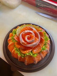 a plate with salmon and lettuce on it, next to a knife and some other items