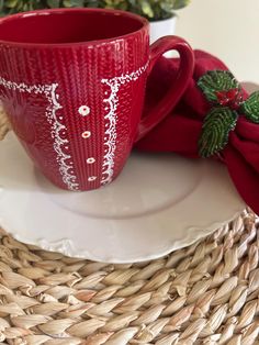 a red coffee cup sitting on top of a white plate