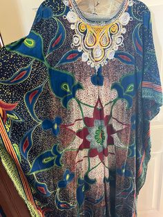 This is a gorgeous homemade kaftan with hand embroidery.  I believe the fabric is a heavy cotton.  Almost like Kente Kloth.  There are no labels or tags.  The kaftan measures 23" across from seam to seam.  I think it is an XL to a 2X.  The colors are so vibrant and the fabric is heavy and beautiful. Bohemian Multicolor Print V-neck Kaftan, Multicolor V-neck Kaftan With Batik Print, Traditional Multicolor V-neck Kimono, Traditional Multicolor Kimono For Beach Cover-up, Festive Bohemian Floral Print Kaftan, Traditional Printed Kimono For Beach Cover-up, Green Bohemian Tunic Kaftan, Bohemian Multicolor Floral Embroidered Poncho, Bohemian Style Long Agbada In Free Size