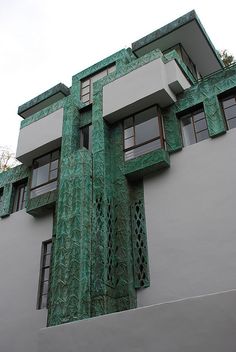 a green and white building with windows on the top floor is painted like an art deco