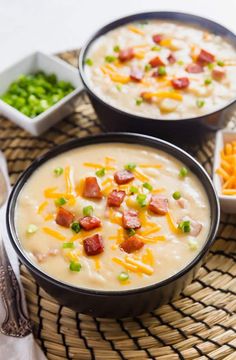 two bowls of potato soup with bacon, cheese and green onions on a woven place mat