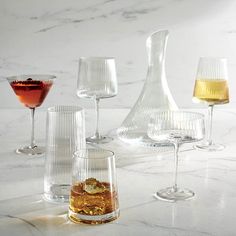 several different glasses are lined up next to each other on a marble counter top,