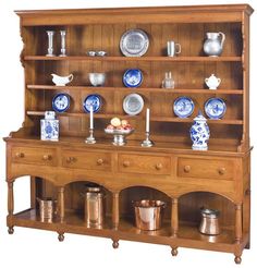 an old wooden china cabinet with blue and white dishes on it's shelves,