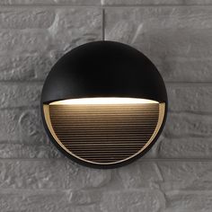 a black and gold light mounted on a brick wall next to a white brick wall