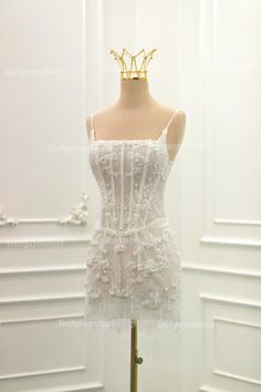 a mannequin with a white dress on display in a store front window, wearing a gold crown