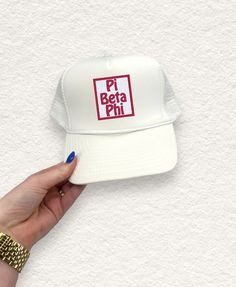 a woman's hand holding up a white hat with the words pit bera phi on it