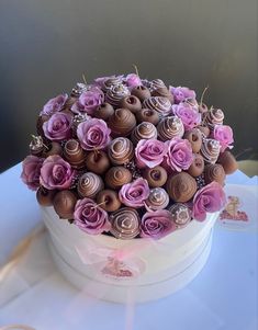 a white box filled with pink and brown cupcakes on top of a table