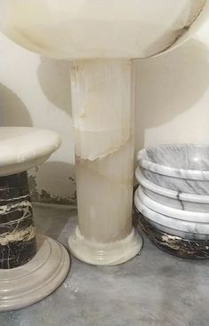 a white pedestal sink sitting next to a stack of plates on the floor in a bathroom