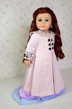 a doll with long hair wearing a pink coat