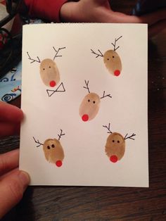 a hand holding up a piece of paper with reindeer's faces drawn on it