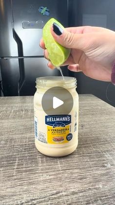 a person holding an apple over a jar of mayonnaise