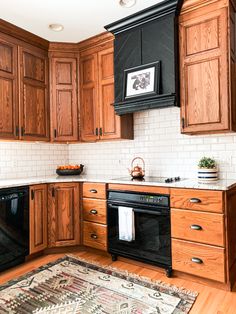 a kitchen with wooden cabinets and black appliances in the corner, including an area rug on the floor