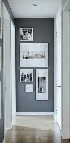 a hallway with pictures on the wall and wooden floors in front of it, along with white framed photos