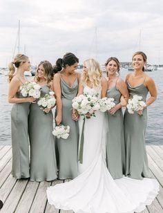 a group of women standing next to each other on a wooden dock near the water