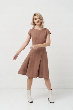 a woman in a brown dress poses for the camera with her hand on her hip