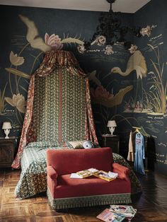 a bedroom with a canopy bed, red chair and wallpapered walls in the background