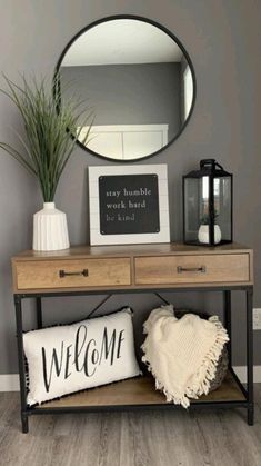 a wooden table topped with a mirror next to a plant and a welcome sign on top of it