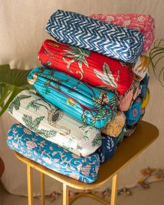 a stack of folded towels sitting on top of a wooden table next to a potted plant