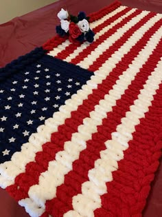 an american flag crocheted blanket with flowers on the top and bottom, sitting on a table