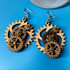 two gears are attached to wooden earrings on a blue surface