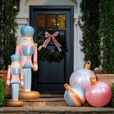 an assortment of christmas decorations on steps outside a house with a wreath and nutcracker