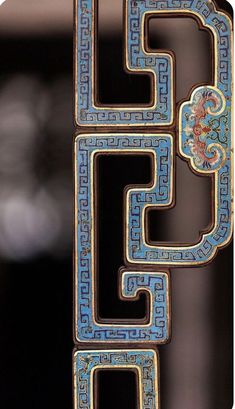 an ornate blue and gold object hanging from a metal rod with intricate designs on it