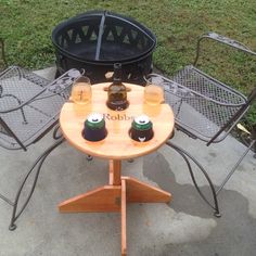 an outdoor table with two beer bottles on it next to a trash can and chair