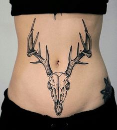 a woman's stomach with a deer skull and antlers tattoo on the side