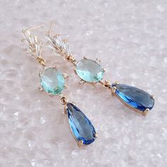 "Gold Blue Earrings for brides, weddings and bridal showers. The perfect gift earrings for bridesmaids, mother of the groom, or mother of the bride. Find earrings for bridal bachelorette party or other special occasions here. A pretty pair of classic teardrop glass crystal earrings embellished with twinkling cubic zirconia crystals on a gold finish. These dainty CZ  and glass crystal drop earrings make a gorgeous bridesmaid gift and make a timeless wedding earring too. Blue glass crystals add a fun pop of color and a great way to sneak in a \"something blue\" into your bridal or bridesmaid ensemble. Simply stunning!  These beautiful blue statement earrings will complement any bridal style and make the perfect gift for bridesmaids too. The Details: * Made with premium quality crystals * Sto Elegant Blue Crystal Earrings, Elegant Blue Teardrop Earrings For Formal Occasions, Elegant Blue Bridal Earrings For Bridesmaids, Blue Dangle Earrings For Bridesmaids, Blue Dangle Crystal Earrings For Formal Occasions, Blue Crystal Drop Earrings For Formal Occasions, Blue Bridal Earrings For Formal Occasions, Elegant Blue Drop Crystal Earrings, Elegant Blue Teardrop Bridal Earrings