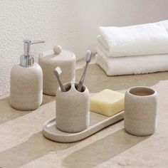 bathroom accessories including soap dispenser, toothbrush holder and soap dish on counter