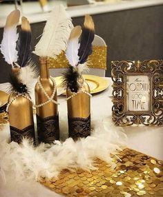 gold and white feathers are on the table with some bottles in front of it, along with a photo frame