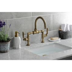 a bathroom sink with two faucets and soap dispensers on the counter