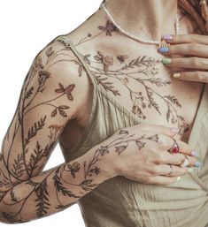 a woman with tattoos on her arms and chest is holding something in her right hand