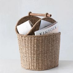 a wicker basket filled with books on top of a white table next to a wooden stick